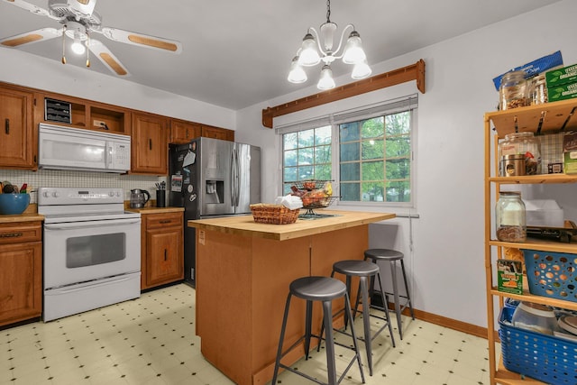 kitchen with white appliances, wooden counters, light flooring, a chandelier, and a breakfast bar