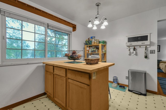 kitchen featuring wood counters, light flooring, baseboards, a chandelier, and hanging light fixtures