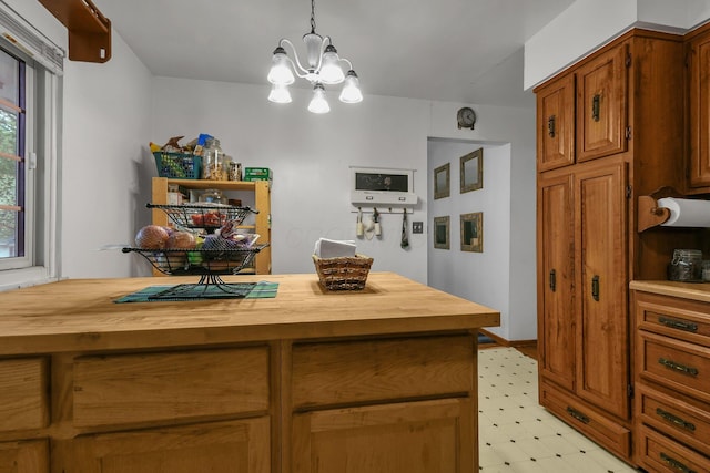 kitchen featuring butcher block counters, light flooring, a chandelier, and brown cabinetry