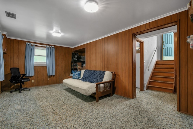 sitting room with ornamental molding, stairs, wood walls, and carpet floors