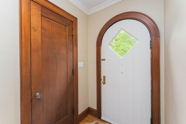 entryway featuring arched walkways, baseboards, and crown molding