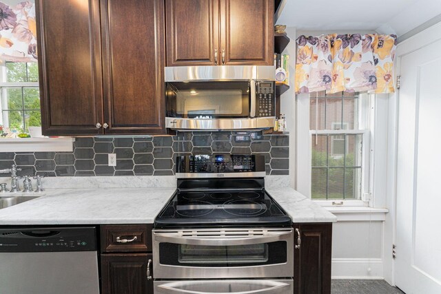 kitchen with appliances with stainless steel finishes, baseboards, tasteful backsplash, and dark brown cabinetry