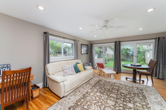 living room with light wood-type flooring, recessed lighting, a ceiling fan, and baseboards