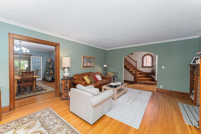 living room with arched walkways, a chandelier, healthy amount of natural light, wood finished floors, and ornamental molding