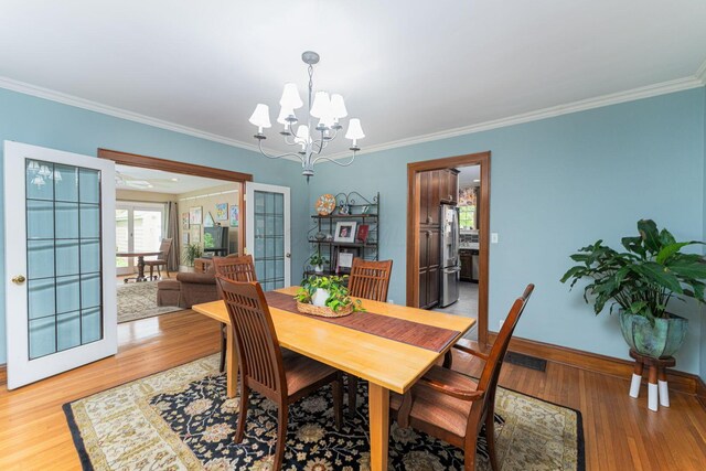 dining space featuring ornamental molding, a chandelier, light wood-style floors, and baseboards