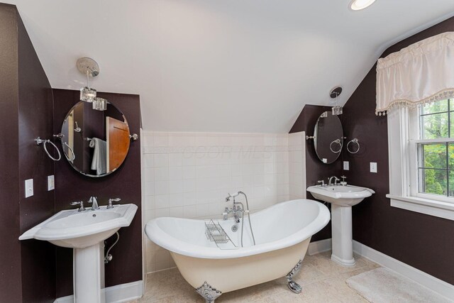 full bath featuring lofted ceiling, a soaking tub, baseboards, and tile patterned floors