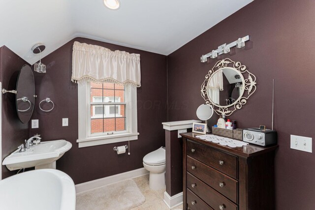 bathroom with lofted ceiling, a sink, toilet, baseboards, and tile patterned flooring