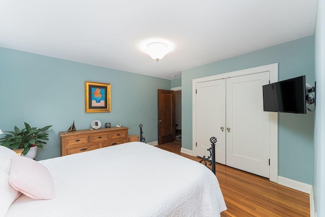 bedroom featuring wood finished floors, baseboards, and a closet