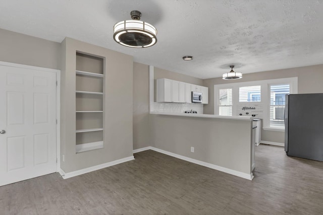 1617 Arlington Ave, Columbus, OH 43211 - kitchen featuring stainless steel appliances, built in features, wood finished floors, white cabinets, and a textured ceiling