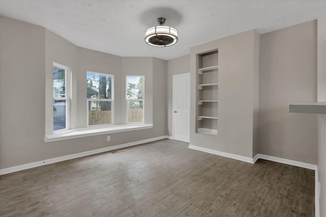 1617 Arlington Ave, Columbus, OH 43211 - unfurnished dining area featuring built in features, wood finished floors, baseboards, and a textured ceiling