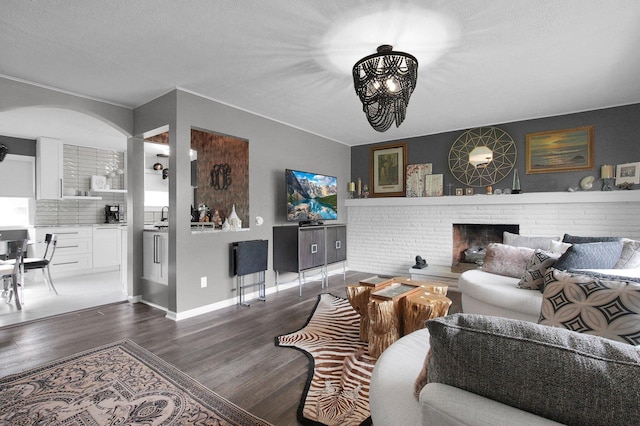 3130 Marwick Rd, Columbus, OH 43232 - living room featuring wood finished floors, a chandelier, arched walkways, a fireplace, and baseboards