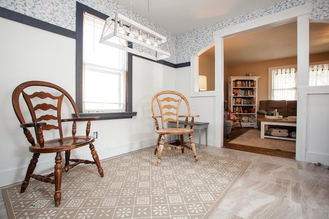 sitting room with wallpapered walls, healthy amount of natural light, and a chandelier