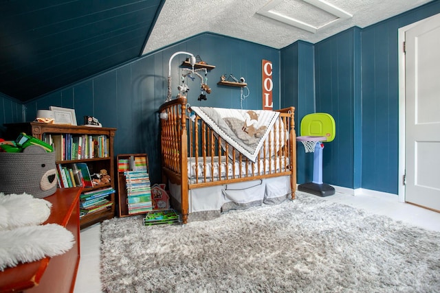 bedroom featuring lofted ceiling, attic access, and a decorative wall