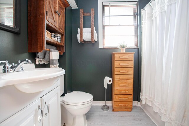 full bathroom featuring vanity, wood finished floors, toilet, a shower with shower curtain, and baseboards