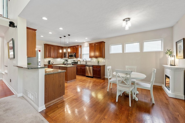 6674 Letterman Dr, Powell, OH 43065 - kitchen featuring stainless steel appliances, stone counters, brown cabinets, recessed lighting, and a center island