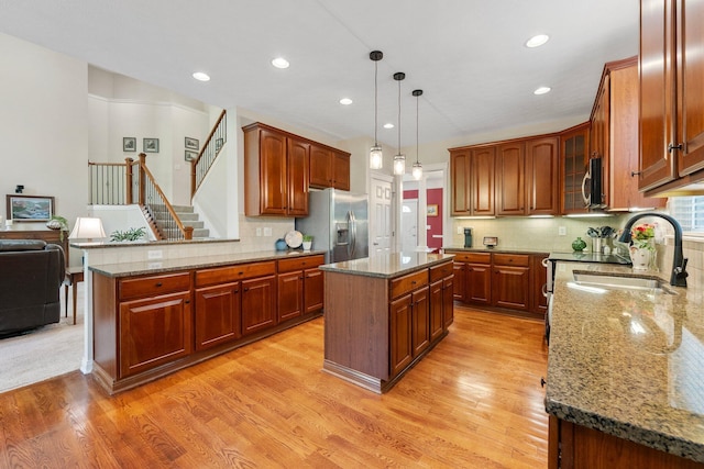 6674 Letterman Dr, Powell, OH 43065 - kitchen featuring a sink, light wood-style flooring, stainless steel appliances, stone countertops, and a center island