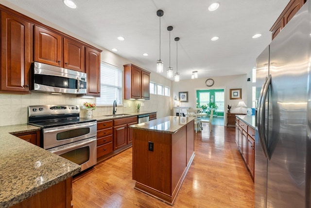 6674 Letterman Dr, Powell, OH 43065 - kitchen with appliances with stainless steel finishes, a sink, a kitchen island, dark stone counters, and backsplash