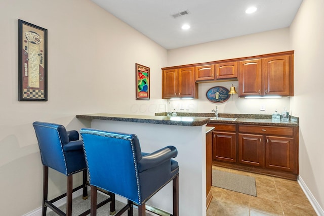 6674 Letterman Dr, Powell, OH 43065 - kitchen with a breakfast bar area, dark countertops, baseboards, a peninsula, and recessed lighting
