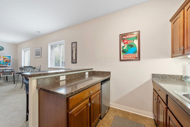 6674 Letterman Dr, Powell, OH 43065 - kitchen featuring stainless steel dishwasher, a peninsula, a kitchen breakfast bar, baseboards, and brown cabinetry