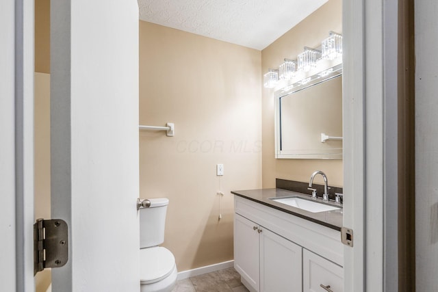 bathroom with toilet, vanity, baseboards, tile patterned floors, and a textured ceiling
