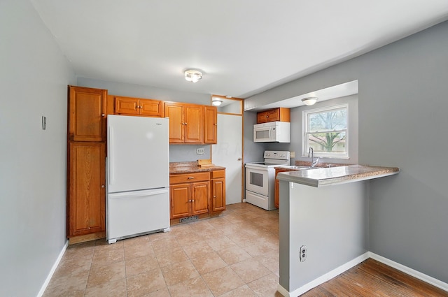 kitchen featuring white appliances, brown cabinets, baseboards, and light countertops