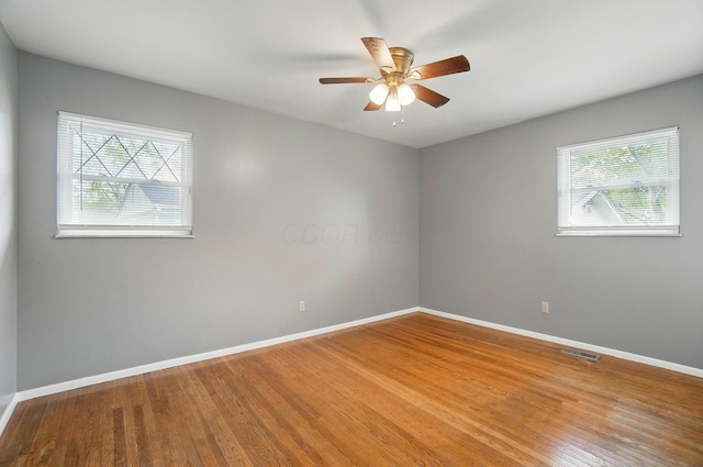 spare room with plenty of natural light, baseboards, and wood finished floors
