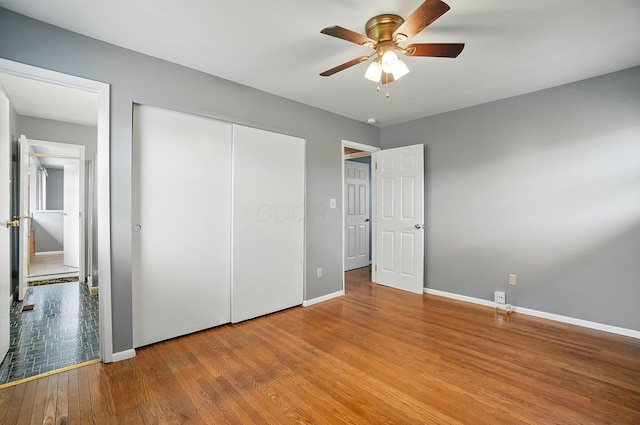 unfurnished bedroom featuring wood-type flooring, baseboards, and a closet