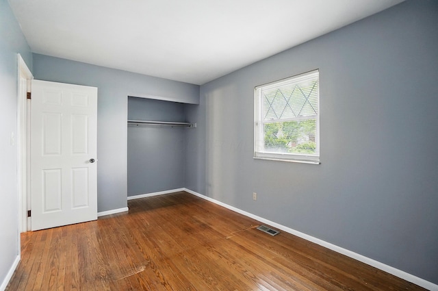 unfurnished bedroom featuring wood finished floors, baseboards, and a closet