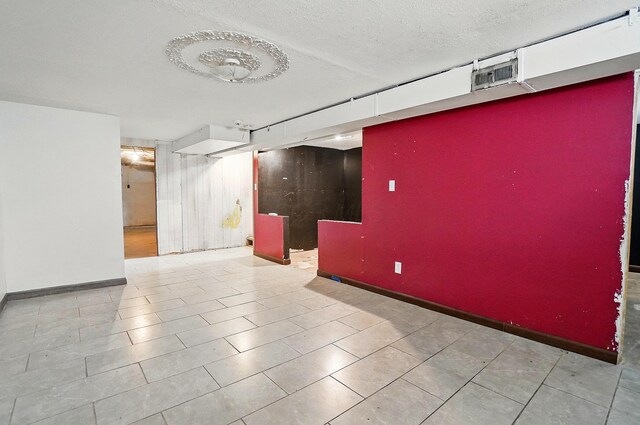 empty room featuring a textured ceiling, baseboards, and tile patterned flooring