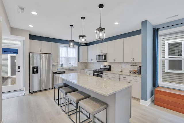 1242 N Grant Ave, Columbus, OH 43201 - kitchen with appliances with stainless steel finishes, a sink, light wood-type flooring, decorative backsplash, and a breakfast bar