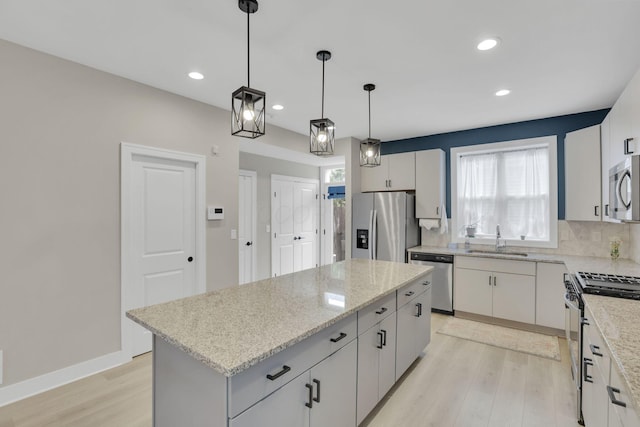 1242 N Grant Ave, Columbus, OH 43201 - kitchen with appliances with stainless steel finishes, a sink, light wood-style floors, a kitchen island, and healthy amount of natural light