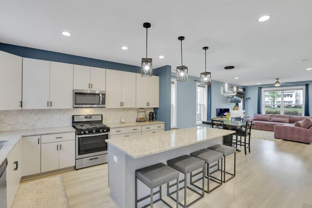 1242 N Grant Ave, Columbus, OH 43201 - kitchen with stainless steel appliances, decorative backsplash, light wood-style flooring, open floor plan, and recessed lighting