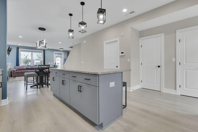 1242 N Grant Ave, Columbus, OH 43201 - kitchen featuring gray cabinets, light wood-style flooring, a center island, open floor plan, and decorative light fixtures