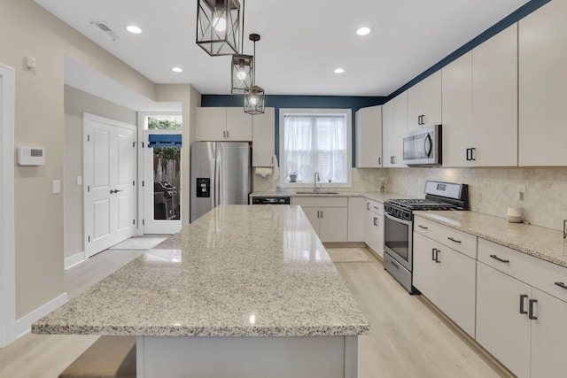 1242 N Grant Ave, Columbus, OH 43201 - kitchen featuring stainless steel appliances, a sink, a kitchen island, decorative backsplash, and light stone counters