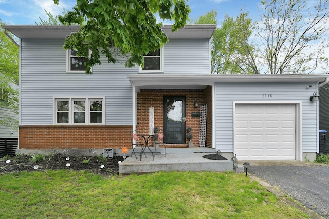 6528 Shenandoah Dr, Reynoldsburg, OH 43068 - view of front facade with brick siding, an attached garage, driveway, a front yard, and a porch