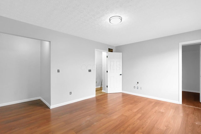 5744 Burcale Dr, Galloway, OH 43119 - unfurnished bedroom featuring light wood-type flooring, baseboards, a walk in closet, a textured ceiling, and a closet
