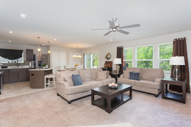 living area featuring a ceiling fan, light carpet, a chandelier, and recessed lighting