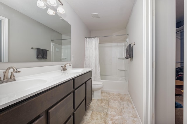 full bathroom featuring shower / bath combination with curtain, toilet, double vanity, stone finish floors, and baseboards