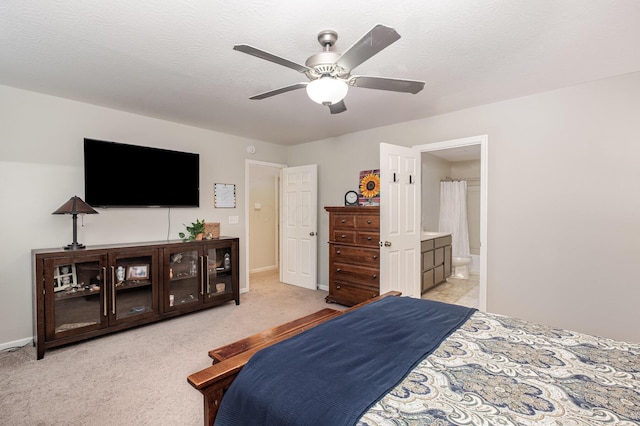 bedroom featuring baseboards, ensuite bathroom, a ceiling fan, and light carpet