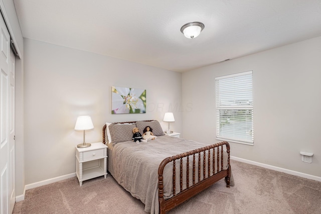 bedroom featuring light carpet, baseboards, and a closet