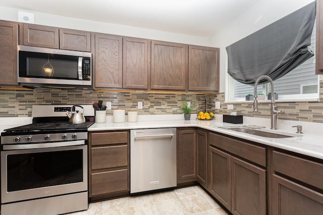kitchen with appliances with stainless steel finishes, a sink, light countertops, and tasteful backsplash