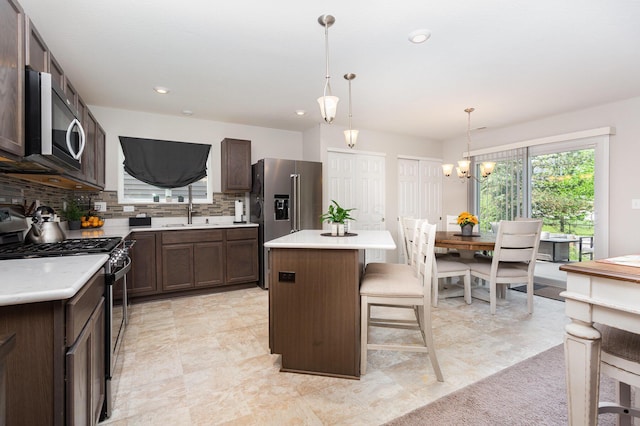 kitchen with stainless steel appliances, a center island, a kitchen bar, tasteful backsplash, and light countertops