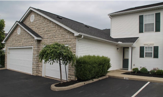 5176 Lodi Dr Unit 26B, Canal Winchester, OH 43110 - view of side of property featuring stone siding, driveway, and an attached garage