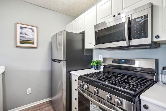 5176 Lodi Dr Unit 26B, Canal Winchester, OH 43110 - kitchen featuring appliances with stainless steel finishes, white cabinetry, light countertops, baseboards, and dark wood-type flooring