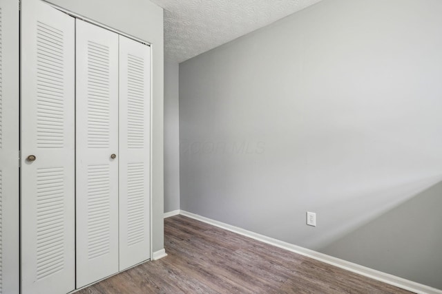 5176 Lodi Dr Unit 26B, Canal Winchester, OH 43110 - unfurnished bedroom featuring a closet, wood finished floors, baseboards, and a textured ceiling