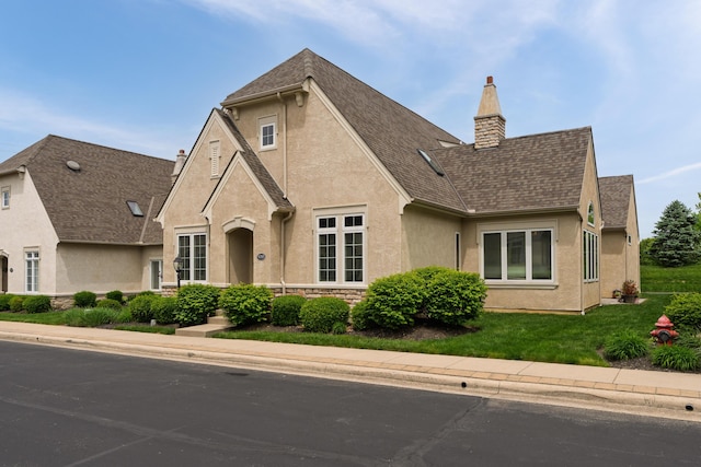 9785 Kingston Cir, Powell, OH 43065 - view of front facade with stucco siding, a chimney, roof with shingles, stone siding, and a front lawn