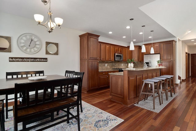 9785 Kingston Cir, Powell, OH 43065 - kitchen with appliances with stainless steel finishes, a center island with sink, backsplash, dark wood-type flooring, and recessed lighting