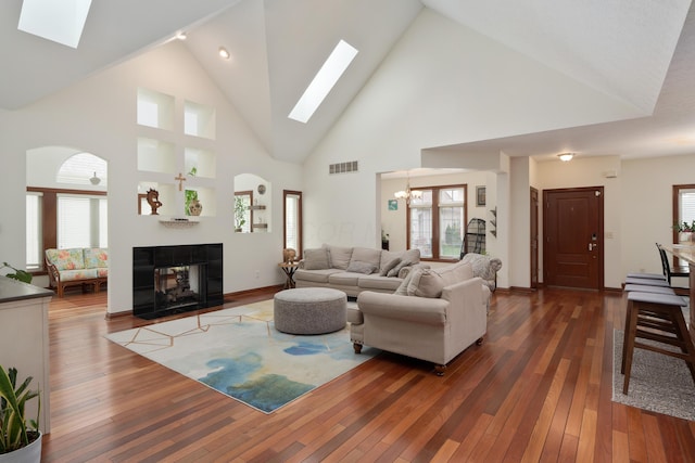 9785 Kingston Cir, Powell, OH 43065 - living room featuring a skylight, a chandelier, a fireplace, high vaulted ceiling, and dark wood-style flooring