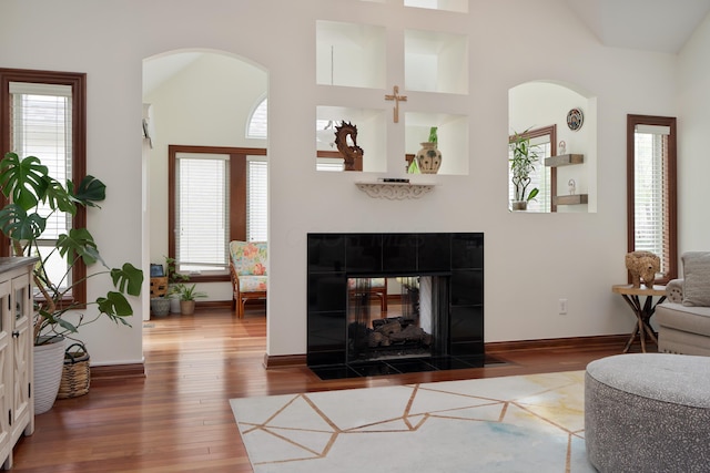 9785 Kingston Cir, Powell, OH 43065 - living area with dark wood-type flooring, arched walkways, a tile fireplace, and baseboards