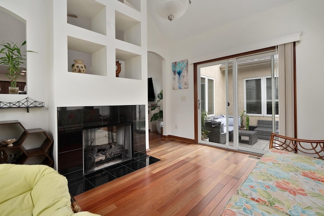 9785 Kingston Cir, Powell, OH 43065 - living room with hardwood / wood-style floors, arched walkways, baseboards, a tiled fireplace, and high vaulted ceiling